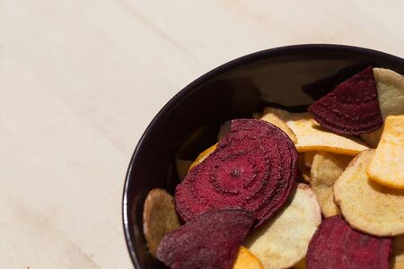 Healthy colorful vegetable chips in purple bowlの写真素材