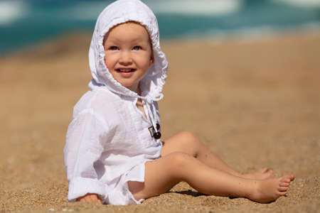 Little girl sitting on the beach on the sand.の写真素材