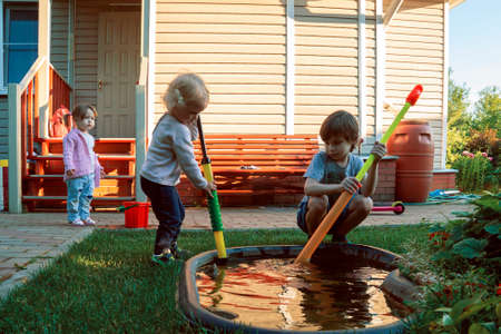 Children play in the garden against the background of the country house.