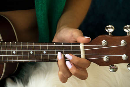 Closeup of hand of young woman playing ukulele.