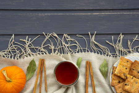 Autumn flatlay with pumpkin, cookies, clay cup with tea and cinnamon chopsticks on gray wooden background.の写真素材