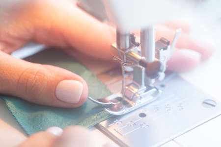 Female hands sewing on a sewing machine