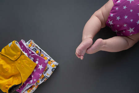 Reusable colorful diapers and baby wearing reusable diapers flatlay. Eco trend, caring about nature lifestyle, responsible consumption conceptの写真素材