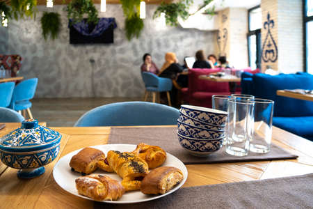 Interior of uzbek cafe with pastries in the foreground and blurred visitors in the background.のeditorial素材