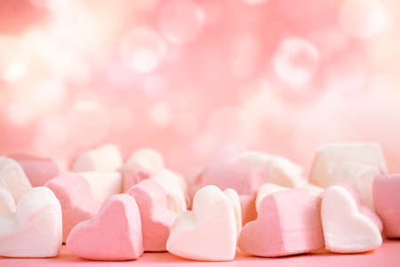 Pink and white marshmallows in the shape of hearts on a pink abstract background with bokeh.の写真素材