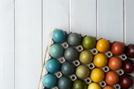 Set of colorful easter eggs colored with natural dye - turmeric, onion skin, carcade, red cabbage and coffee in cardboard on white wooden background. Gradientの写真素材