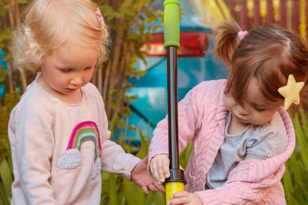Two passionate girls pumping water with childrens pumps from a small pond.の写真素材