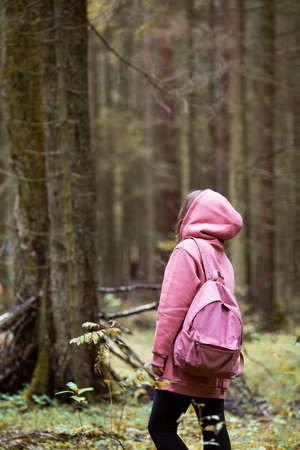 Young woman wearing pink hoodie walking in autumn forestの写真素材