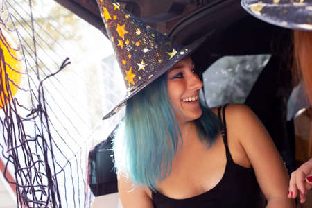Generation Z girl colorful hair witch celebrating Halloween car trunk