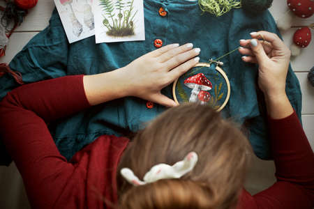 Flat lay with handmade fly agaric mushroom embroidery on dressの写真素材