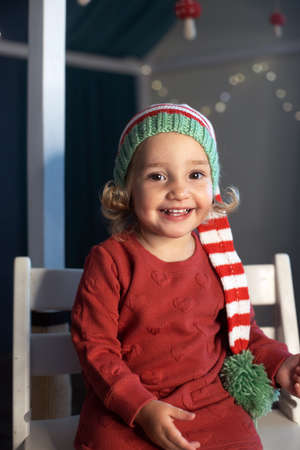 Cheerful little girl Santa hat holding small Christmas tree handsの写真素材