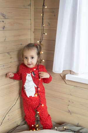 Christmas morning. Toddler girl red pajamas having fun in bedの写真素材