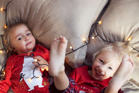 Christmas morning. Two kids girls red pajamas having fun bedの写真素材