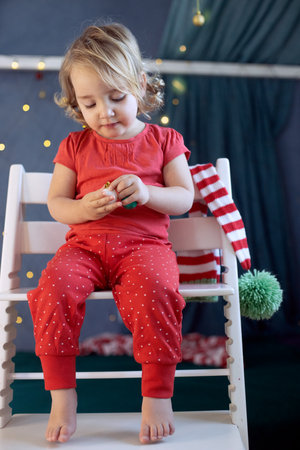Kid girl red pajamas decorating room Christmas. Winter holidays, new year eveの写真素材