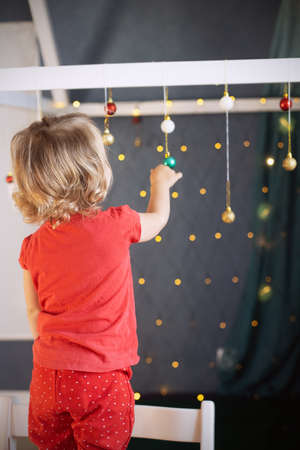 Kid girl red pajamas decorating room Christmas. Winter holidays, new year eveの写真素材