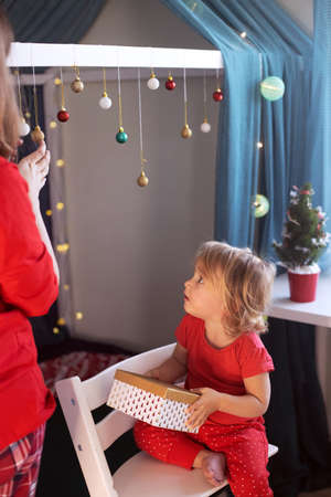 Mom daughter in red pajamas decorating kids room for Christmasの写真素材