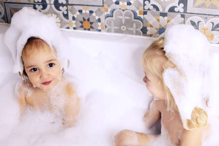 Two kids little girls sisters having fun in bathroom playing with bath foam. Kids personal careの写真素材