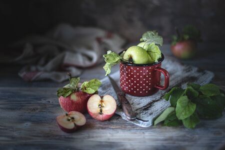 Red and green apples in a red iron bowlの写真素材