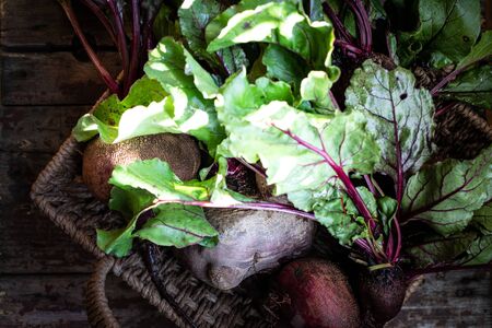 Fresh organic red beets with leaves in a wicker basket on a wooden table. Natural organic...