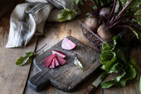 Fresh organic red beets with leaves in a wicker basket on a wooden table. Natural organic...