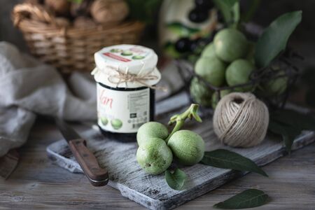 Jar of walnut jam on a wooden table and a group of green walnutsの写真素材