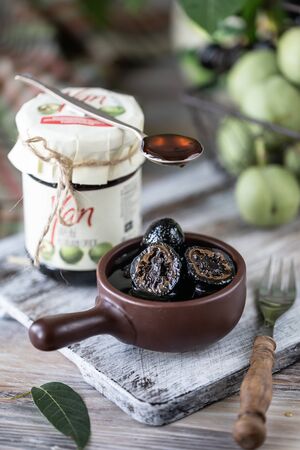 Jar of walnut jam on a wooden table and a group of green walnutsの写真素材