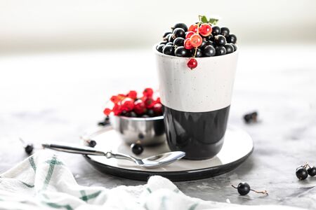 Fresh currants in a ceramic cup: black currants, red currants, selective focus. Place for text. Copy spaceの写真素材