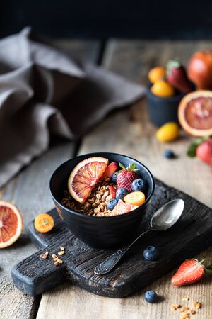 Homemade granola with fresh berries, fruit for Breakfast. The concept of healthy eating. Wooden table. Dark background.の写真素材