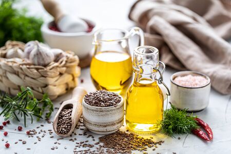 Flaxseed oil in a bottle and ceramic bowl with brown flax seeds and wooden spoon on a white background.の写真素材