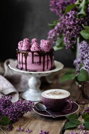 On the table is a beautiful chocolate cake and a bouquet of lilacs.の写真素材