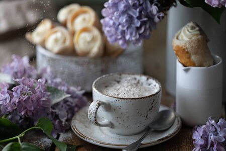 Cup of coffee and cake horns from puff pastry with vanilla cream in a metal box in spring still life...