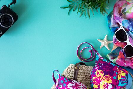 Colorful summer female fashion apartment outfit. Straw bag, sunglasses, palm branches, water with lemon and lime on a blue background, top view, wide composition. Summer fashion, vacation concept. Top view with copy spaceの写真素材