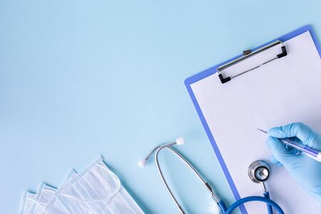 medical concept on a blue background. stethoscope, pills, tablet, notepad, sheet of paper, pen. Medical gloves. Medical maskの写真素材