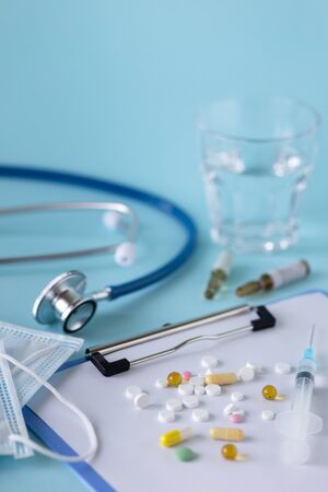 medical concept on a blue background. stethoscope, pills, tablet, notepad, sheet of paper, pen. Medical maskの写真素材