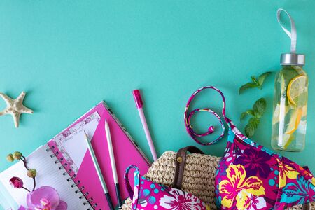 Colorful summer female fashion apartment outfit. Straw bag, sunglasses, palm branches, water with lemon and lime on a blue background, top view, wide composition. Summer fashion, vacation concept. Top view with copy spaceの写真素材