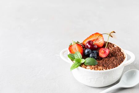 A beautiful portioned serving of Italian tiramisu dessert, garnished with strawberries, cherries and mint on a white background. Copy space for your textの写真素材