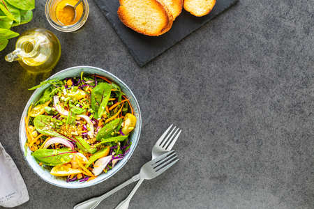 Fresh vegetable and fruit salad in a plate on a black stone background. Top viewの写真素材
