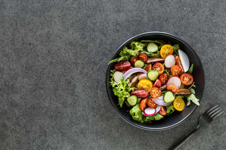 Fresh vegetable salad in a plate on a black background. Top viewの写真素材
