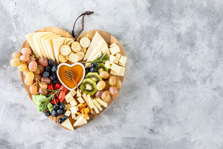 Assorted cheeses on a wooden cutting board in the shape of a heart. copy spaceの写真素材