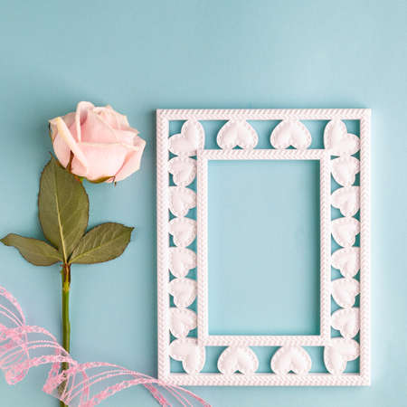Photo frame, one pink rose on a pastel blue background. Valentines day, mothers day, womens day,...