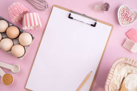 Frame of food ingredients for baking on gently pink pastel background. Cooking flat lay with copy...