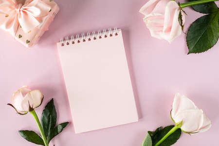 Copy space notepad for your text on a light pink background with pink roses and gift boxes. flat lay. Top view.の写真素材
