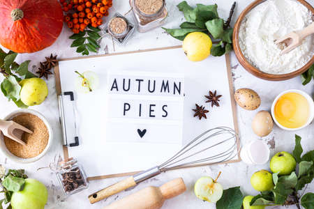 Autumn flat lay with lightbox with the phrase Autumn pies. Top view. Food ingredients for making autumn pumpkin pie on a white stone background.の写真素材