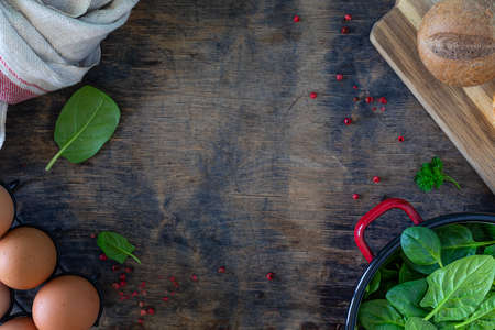 Fresh baby spinach leaves in a bowl and eggs on a wooden table. Top view.の写真素材