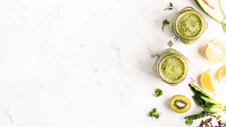 Two jars with a green fruit smoothie on a white background. Healthy eating. top view