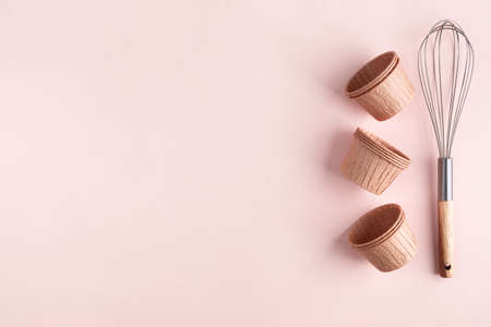 The concept of homemade baking is a whisk for whipping and cupcake molds on a pink background. zero waste. Copy space.の写真素材