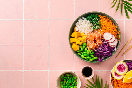 Poke-a bowl with fresh salmon, rice, chuka salad, edamame beans, carrots and red cabbage. Healthy food bowl on pink background, top view, copy spaceの写真素材