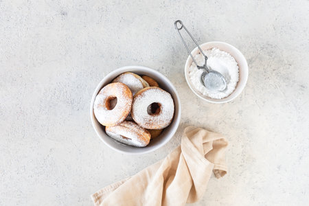 Fresh homemade fried donuts covered with powdered sugar on a white background. Copy space. Top view.の写真素材