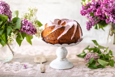 Pound cake traditional vanilla or sour cream flavor, homemade dessert with pink icing on a table with a linen tablecloth.の写真素材