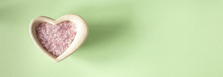 Pink sea salt for cosmetic procedures on a light green background. The banner. Top viewの写真素材